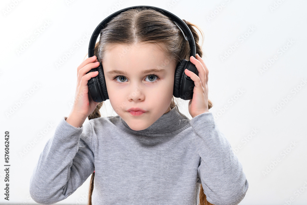 A child with headphones on a white background, a cheerful and beautiful girl with headphones. A child with headphones on a white background, a cheerful and beautiful girl with headphones.
