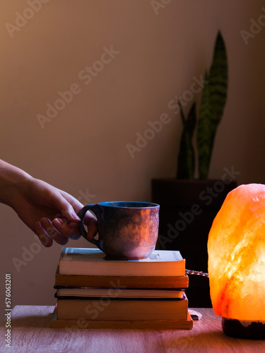 Hand reaching for coffee stacked on books (ID: 576063201)
