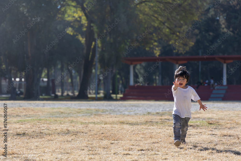 three year old mexican boy playing and running in the park
