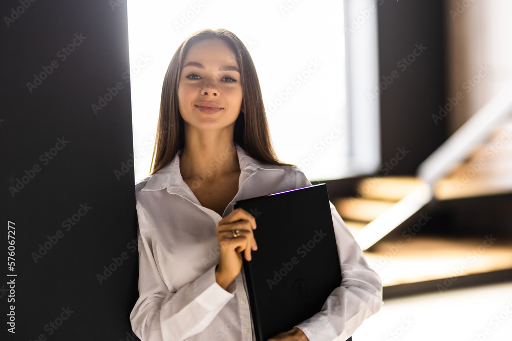 Smiling young woman with laptop in home office Smiling young woman with laptop in home office