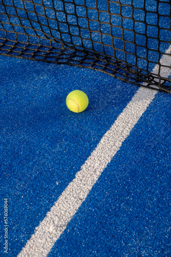 paddle tennis ball in the net of a blue paddle tennis court. © Vic
