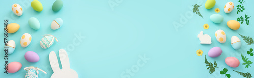 Photography Cute bunny next to easter colorful eggs over blue pastel background