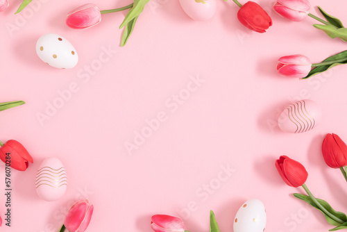 Easter holiday flower composition. Easter eggs and tulip flowers on an isolated pastel pink background. Easter concept. Flat lay, top view, copy space