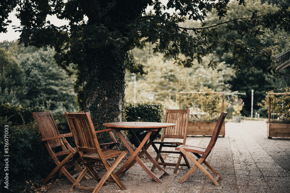 charming outdoor space featuring a sturdy wooden patio with a lovely oak tree providing shade overhead. cozy, rustic vibe, with the wooden furniture and natural surroundings on a patio 