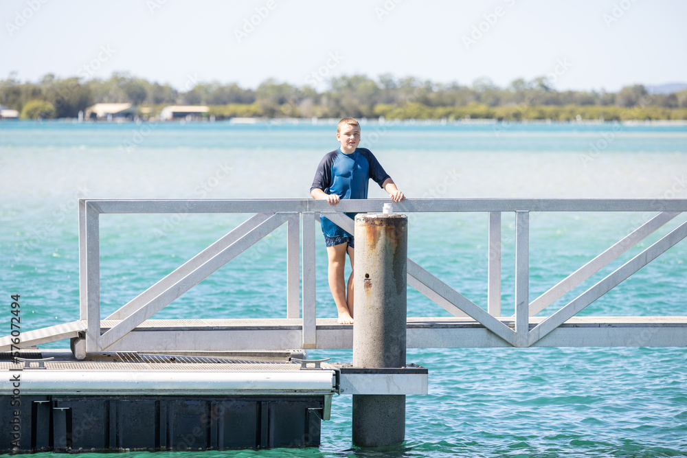 Boy standing on jetty after swimming at Tuncurry, NSW Australia