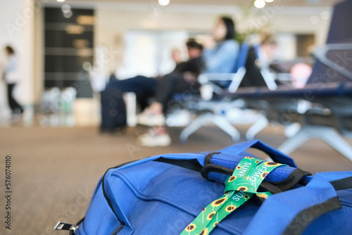 Lanyard of sunflowers, symbol of people with invisible or hidden disabilities, tied on a travel bag on the floor of an airport. 
