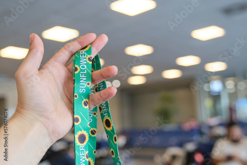 Unrecognizable person holding a lanyard of sunflowers, symbol of people with invisible or hidden disabilities, in a travel context, an airport waiting room.