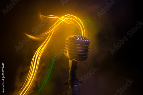 Microphone for sound, music, karaoke in audio studio or stage. Mic technology. Speech broadcast equipment. Microphone in dark room on table with backlight. Selective focus