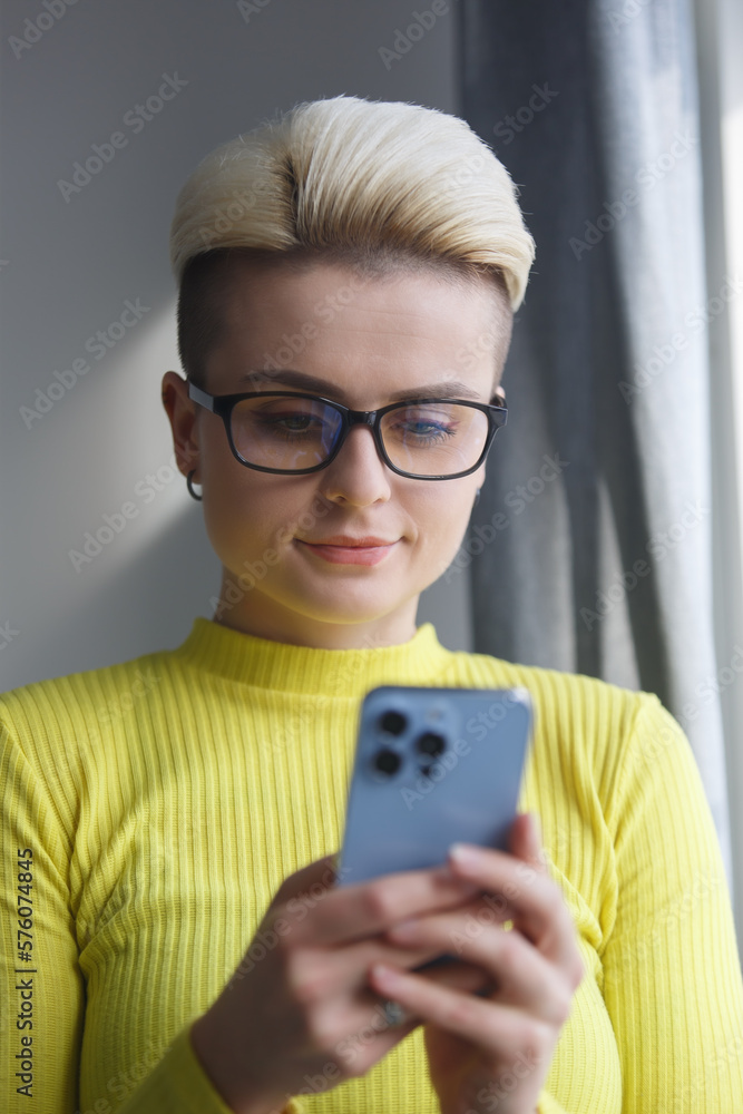 Portrait of beautiful tom boy person typing sms message on mobile phone at home Portrait of beautiful tom boy person typing sms message on mobile phone at home
