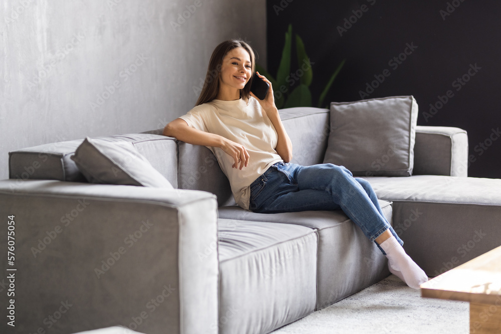 Obraz premium Happy young woman talking phone in loft apartment