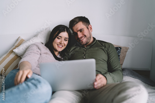 Positive couple watching movie on bed