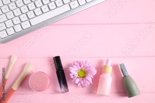 Cosmetics bottles with keyboard on pink table