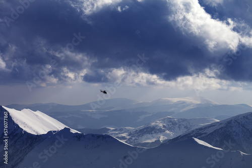 Foto Off-piste slope for heliskiing and helicopter in evening mountains