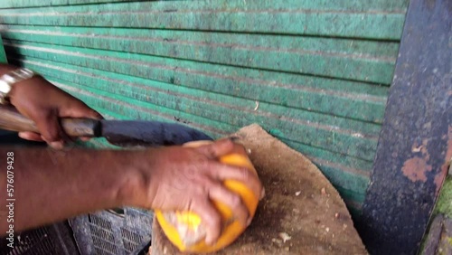 Man cuts the coconut with a knife to make a fresh coconut drinkon a market. Asia, Sri lanka, Kandy.