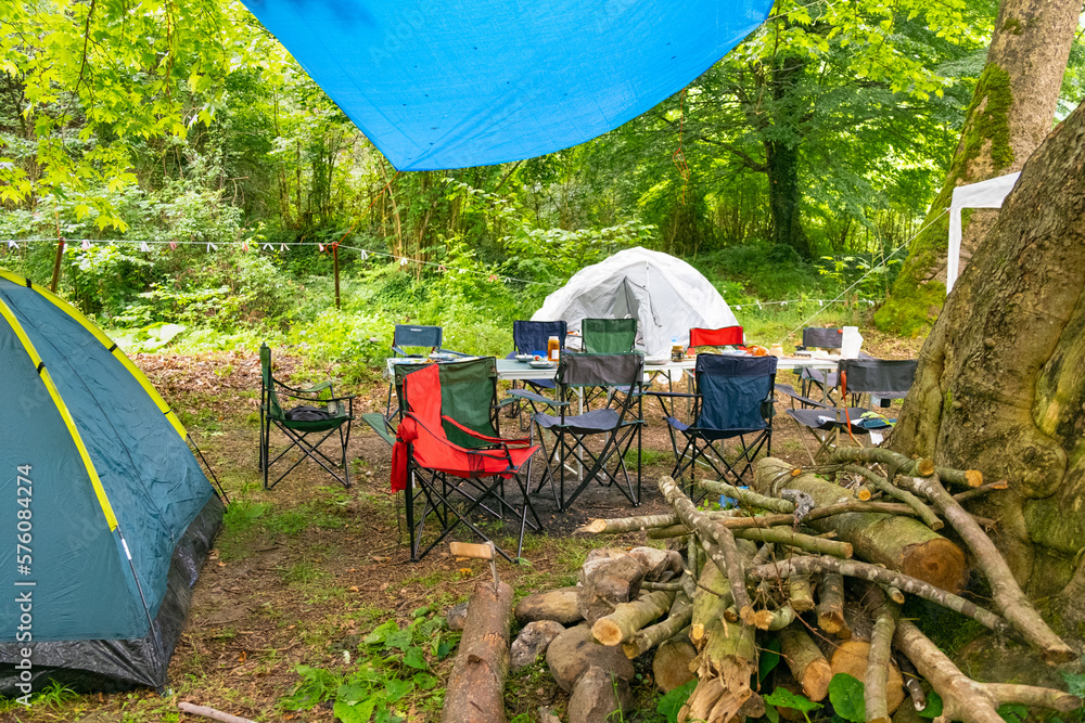 Tent camp in the forest. Folding table and chairs for camping, woods
