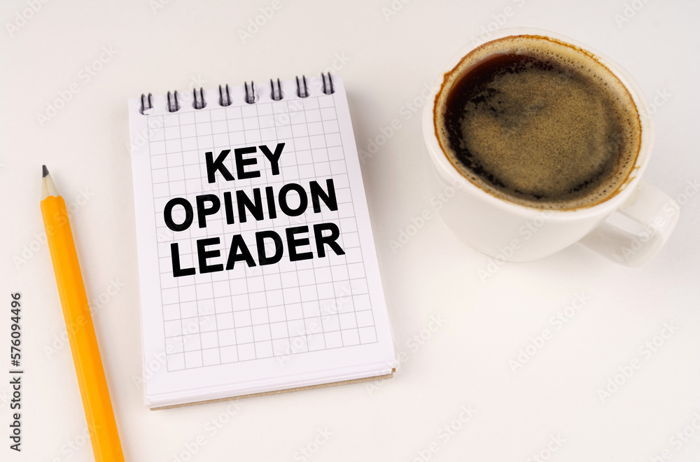 On a white surface, a cup of coffee, a pencil and a notepad with the inscription - KEY OPINION LEADER On a white surface, a cup of coffee, a pencil and a notepad with the inscription - KEY OPINION LEADER