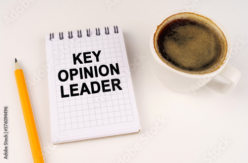 On a white surface, a cup of coffee, a pencil and a notepad with the inscription - KEY OPINION LEADER