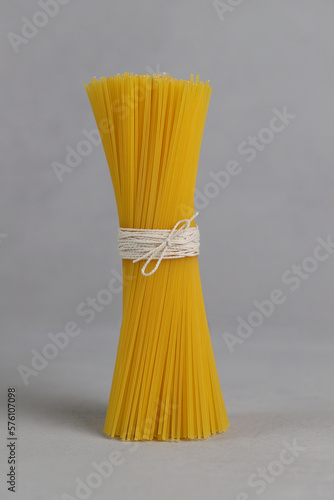 Bunch of spaghetti tied with a rope on a gray background. Gluten free. Spaghetti made of corn and rice flour. Vertical photo