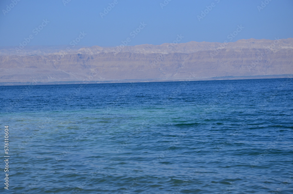 Panoramic view of the beautiful, clear blue Dead Sea shimmering and shining on a bright sunny day in Jordan and the dry land around it. Panoramic view of the beautiful, clear blue Dead Sea shimmering and shining on a bright sunny day in Jordan and the dry land around it.