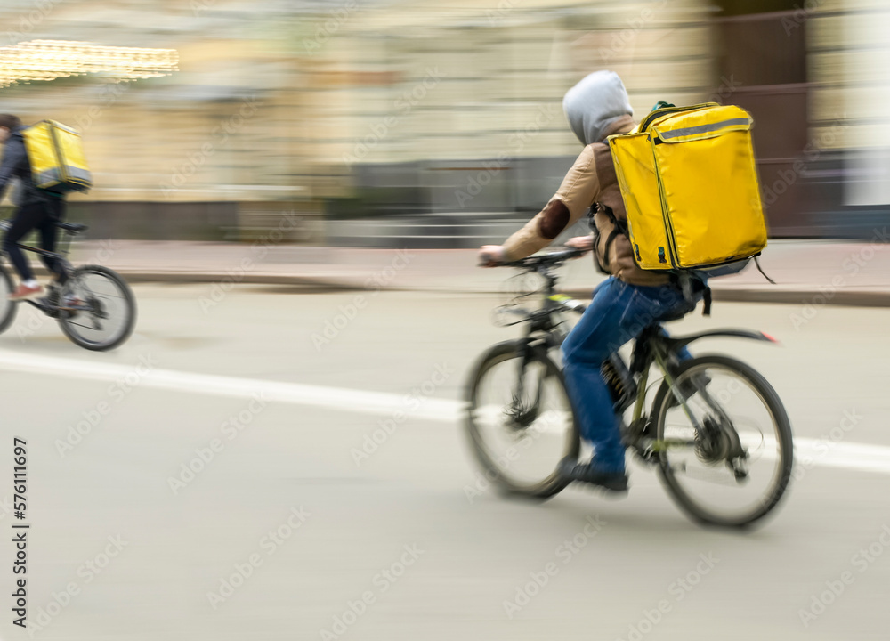 Fototapeta premium Courier on a bike rides down the street