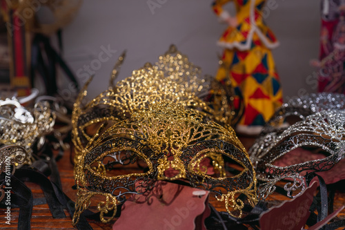 Authentic gold and silver Venetian light masks on the store counter in Venice, Italy. Concept of a masquerade and a fun holiday, real Venetian carnival masks. Selective focus, macro shot, dark key