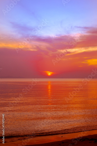 Vertical seascape. Orange sunset on the seashore on a tropical island