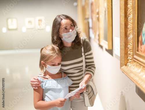 Mom and her daughter in protective masks on a tour of the museum