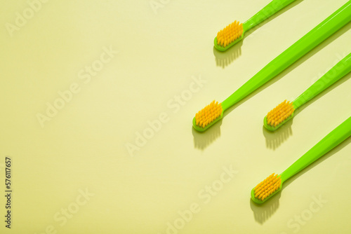 Modern green kids toothbrushes on a yellow background. Copy space for your text 