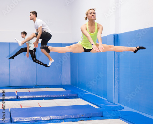 Portrait of focused sports girl during training in trampoline center. Skills and drills of side split..