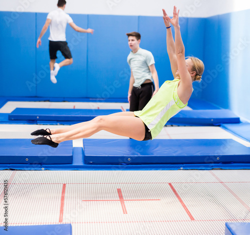 Athletic young woman training jumping movements in indoor trampolines center