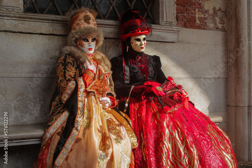 Venetian carnival mask in red and gold costume, traditional carnival in Venice, Italy, two person in costume.