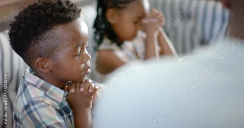 Happy african american family praying before breakfast, in slow motion photo