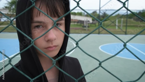 Detained teen by fence. A view of detained young girl by fence on empty playground.
