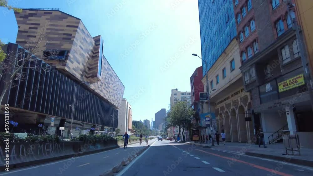 Time lapse in the seventh avenue of Bogota, Colombia in the bike path during the Ciclovia day. Big buildings, cyclists, cars and blue sunny sky Time lapse in the seventh avenue of Bogota, Colombia in the bike path during the Ciclovia day. Big buildings, cyclists, cars and blue sunny sky
