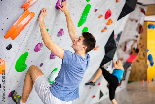 Caucasian young man exercising in climbing gym on wall.
