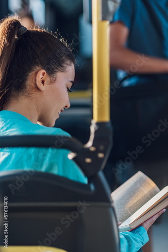 Rear view of a woman riding in a bus and reading a book