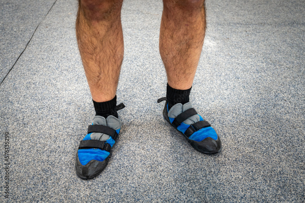 Close up of man's feet wearing indoor climbing wall shoes standing on soft flooring safety mat. Close up of man's feet wearing indoor climbing wall shoes standing on soft flooring safety mat.