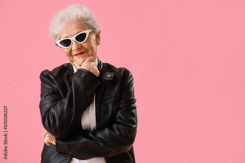 Thoughtful senior woman in sunglasses on pink background