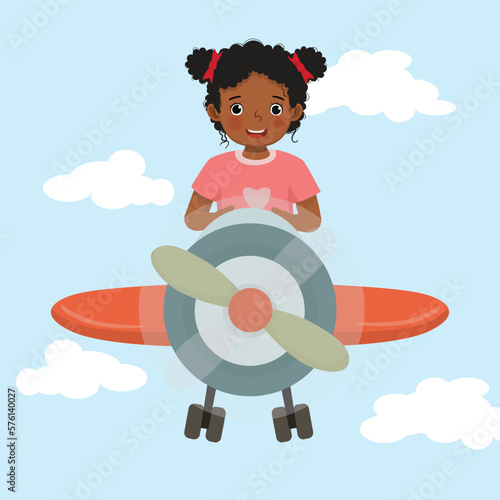 Cute little African girl flying an airplane in the blue sky
