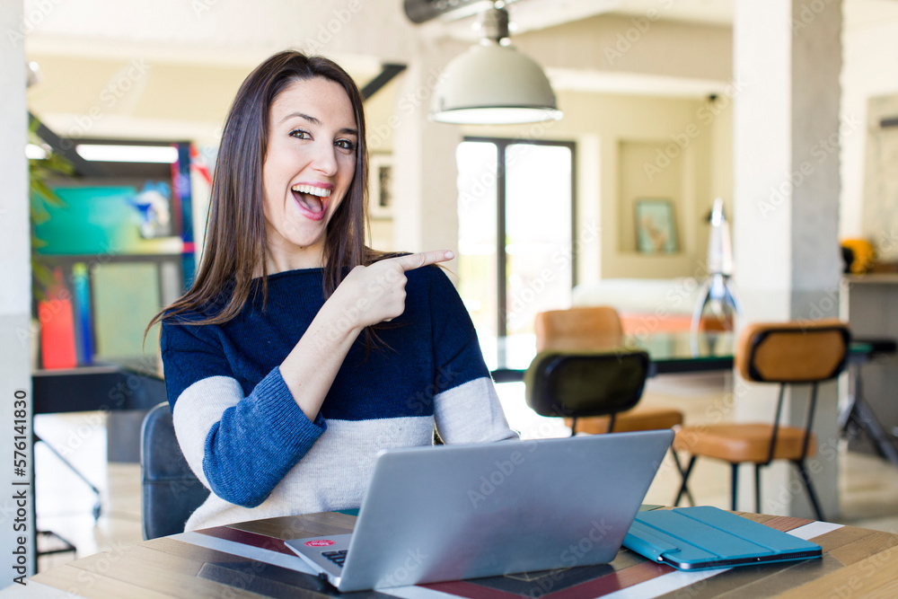 © kues1 - young pretty woman looking excited and surprised pointing to the side. telecommuting concept