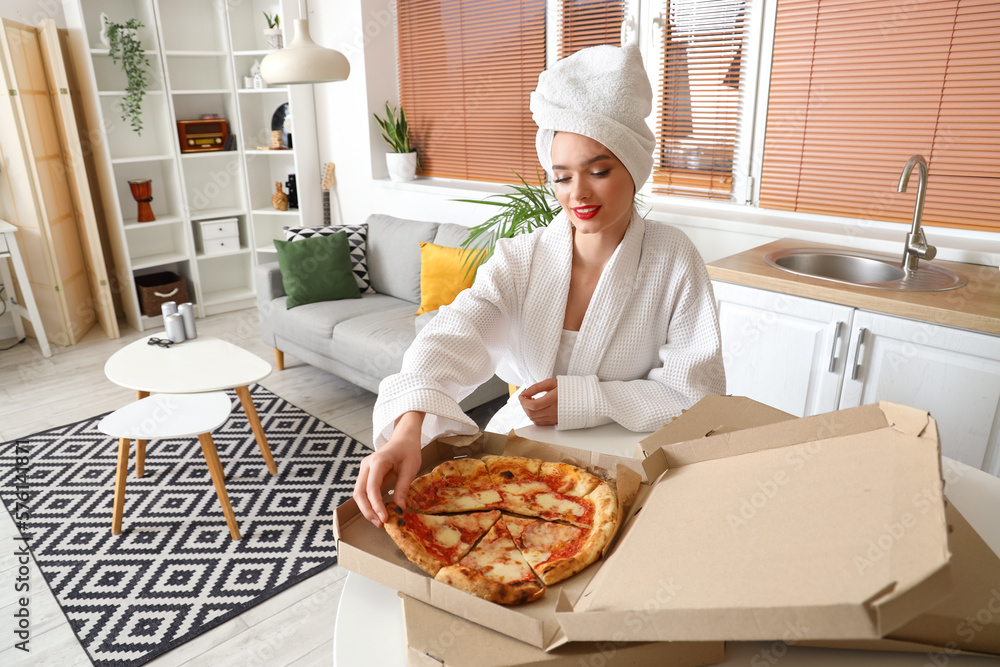 Young woman in bathrobe with tasty pizza sitting at home Young woman in bathrobe with tasty pizza sitting at home