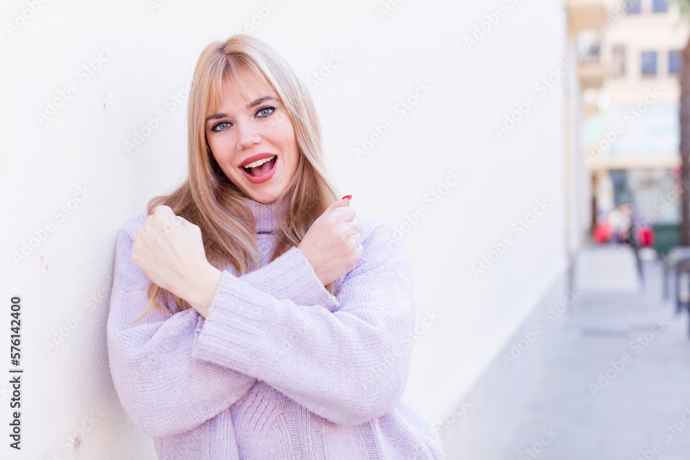 Naklejka premium young pretty woman smiling cheerfully and celebrating, with fists clenched and arms crossed, feeling happy and positive