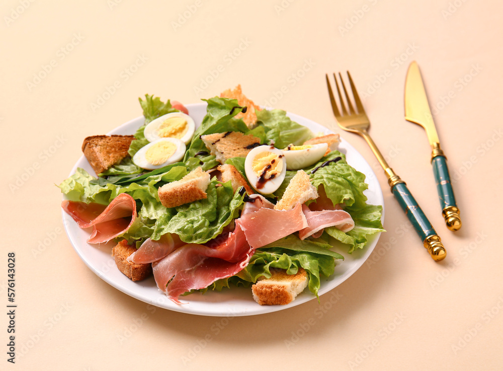 Plate of delicious salad with boiled eggs and jamon on beige background
