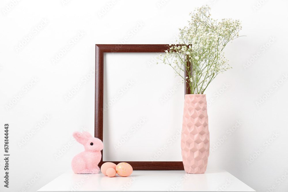 Obraz premium Blank frame, vase with gypsophila flowers, Easter eggs and bunny on white background