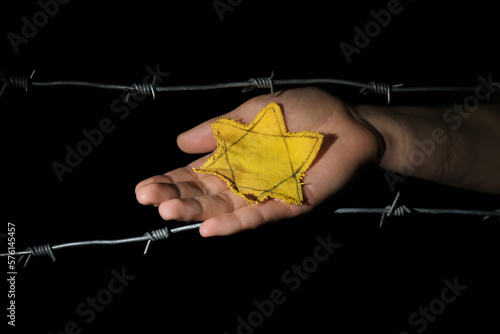 Woman with yellow Jewish badge and barbed wire on dark background. International Holocaust Remembrance Day photo