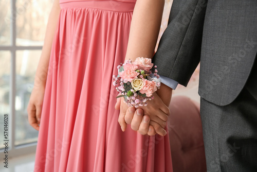 Young woman with corsage and her prom date holding hands, closeup