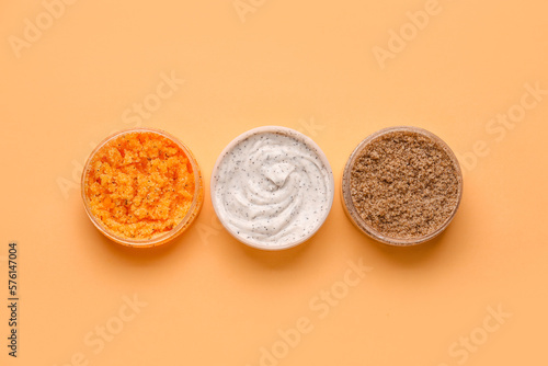 Jars of natural body scrub on color background