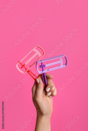 Woman with Jewish rattles for Purim holiday on pink background