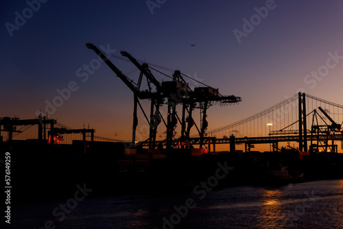 Cranes in a sea port during sunset.