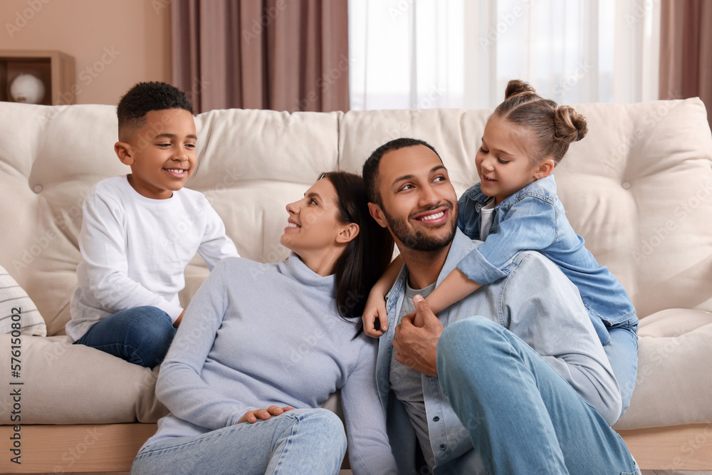 Happy international family with children near sofa at home Happy international family with children near sofa at home